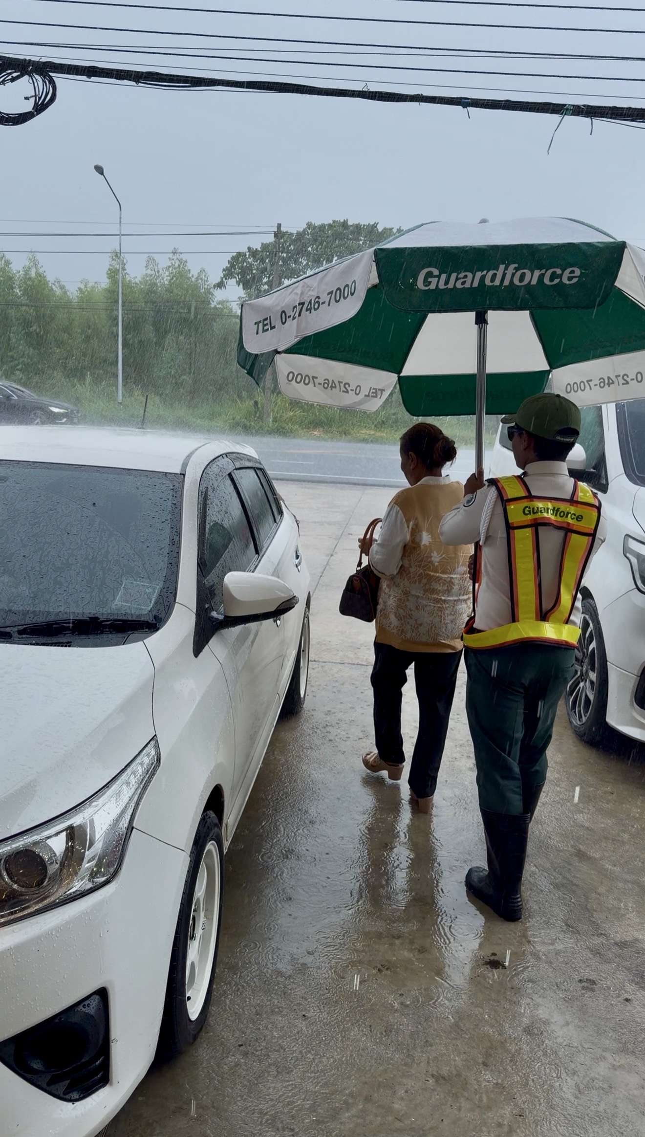 เจ้าหน้าที่รักษาความปลอดภัยดูแลลูกค้าหน้าร้านอุดมรีไซเคิลในวันที่ฝนตก